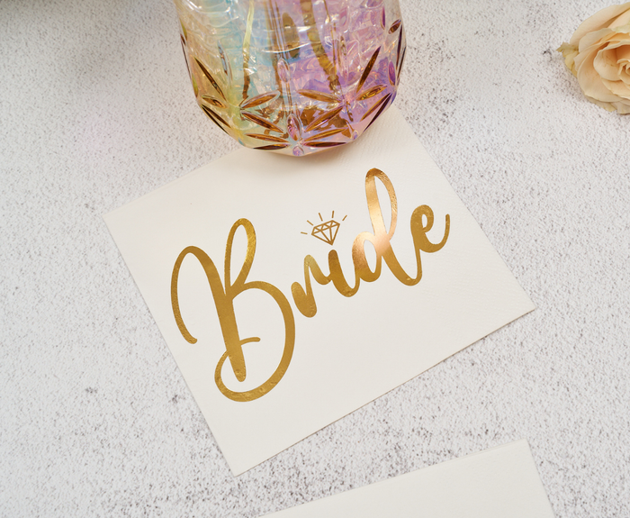 Sugarplum’s Bride Cocktail Napkins (26pk) feature “Bride” in shiny gold script with a diamond accent, and are perfect for adding chic style to bridal showers or bachelorette parties.