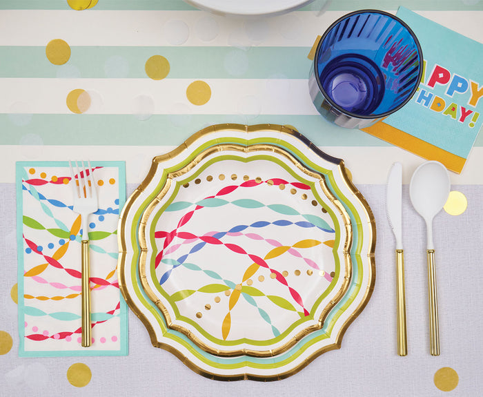The Bright Birthday Table Setting by Sophistiplate features designer disposable plates, gold-trimmed cutlery, a colorful napkin, blue cup, and Happy Birthday card on a pastel striped and polka dot placemat.