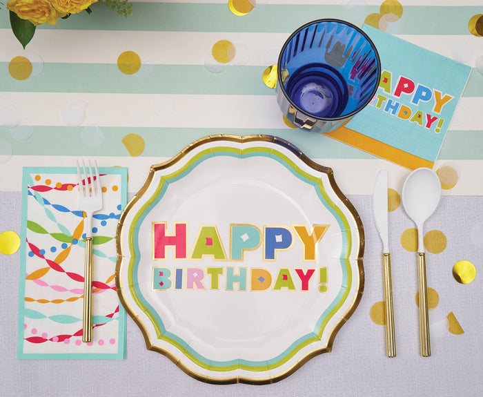 The Sophistiplate Bright Birthday Table Setting features HAPPY BIRTHDAY! designer plates, gold utensils, a blue cup, festive napkins, and gold confetti on a striped disposable tablescape.