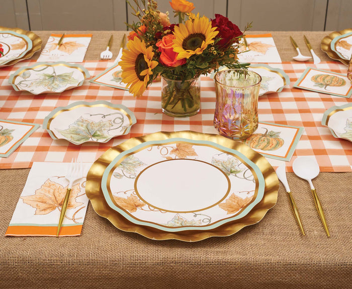 Create a festive autumn table setting with Sophistiplate Bright & Thankful Dinner Plates (8-pack) featuring metallic gold trim, fall-themed napkins, gold utensils, a colorful floral centerpiece, and a plaid tablecloth.