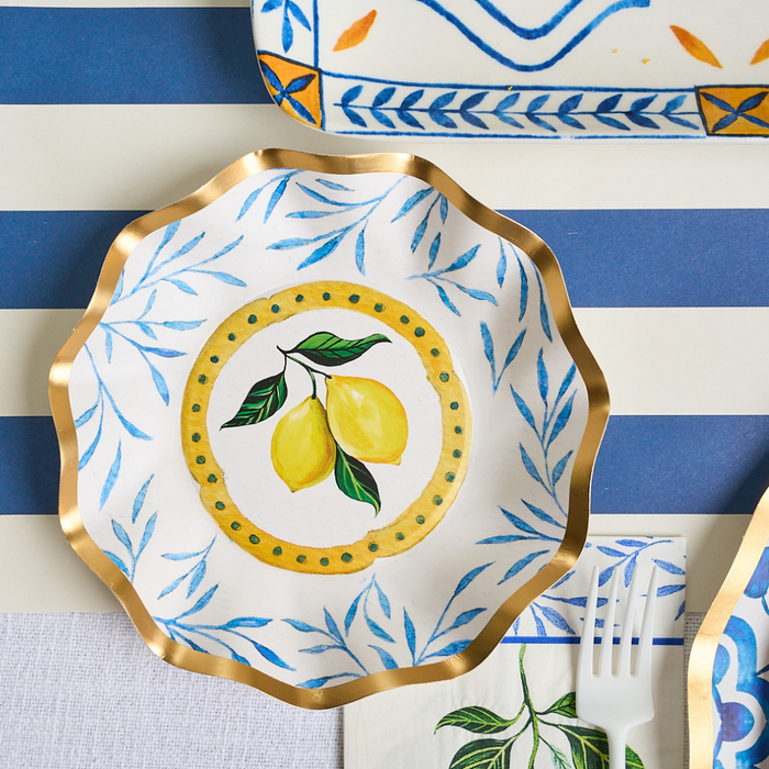 The Capri Coast Table Setting by Sophistiplate LLC features decorative disposable plates with gold scalloped edges and painted yellow lemons, perfect for adding charm to any gathering.