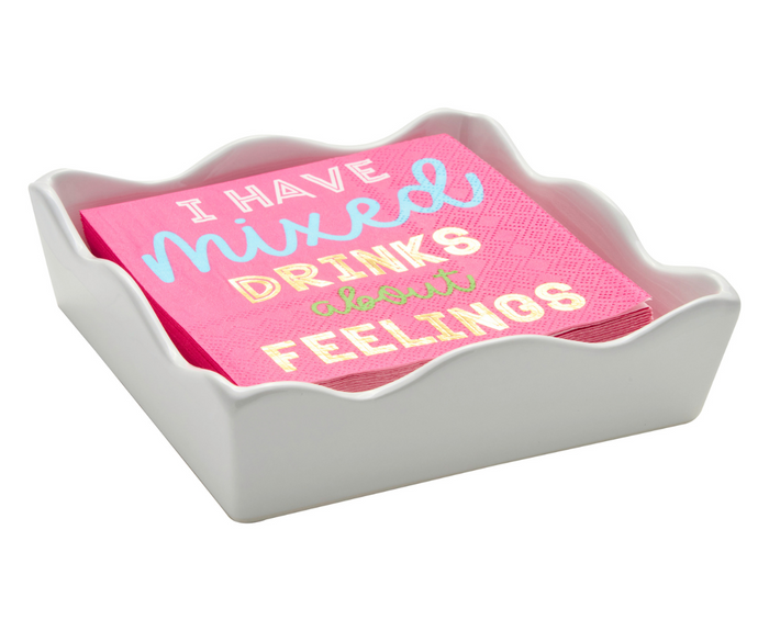 A stack of pink napkins reading "I HAVE mixed DRINKS about FEELINGS" in colorful letters sits in the Sophistiplate Ceramic Cocktail Napkin Tray, featuring a white wavy-edged design.