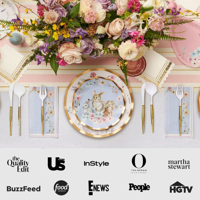 The Ultimate Easter Tablescape for 16: Charming Easter by Sophistiplate LLC features pastel floral arrangements, designer dog-themed plates, gold-rimmed chargers, and cutlery. Outlet logos—BuzzFeed, HGTV, and People—displayed at the bottom.