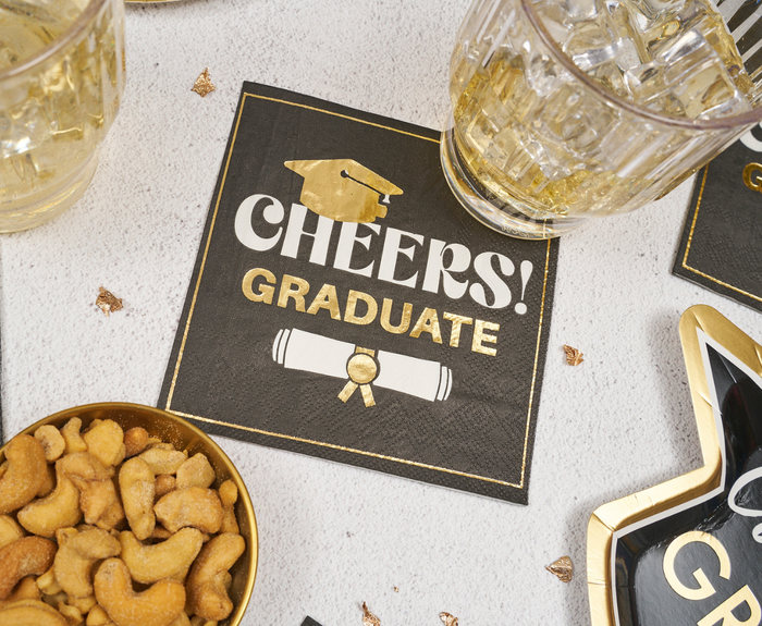 Celebrate with Sugarplum's Cheers Graduate Cocktail Napkins (26pk)—stylish black napkins featuring gold "Cheers! Graduate" text, a cap, and diploma—great for serving drinks and snacks at your graduation party.