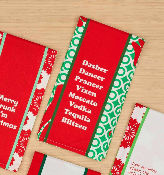 The CHRISTMAS Blitzen Dish Towel by Drinks On Me features red and green kitchen humor, mixing reindeer names with drinks—Dasher, Dancer, Prancer, Vixen, Moscato, Vodka, Tequila, Blitzen—making it a fun housewarming or holiday gift.