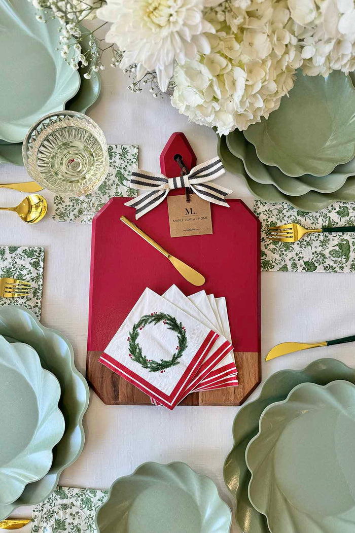 Create a festive table with Sophistiplate’s Christmas Board Gift Kit: Merry & Bright—featuring scalloped green plates, gold cutlery, floral napkins, holiday wreath napkins, and a red & acacia wood charcuterie board—perfect as a hostess gift.