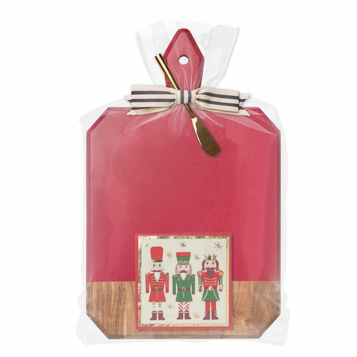 The Sophistiplate Christmas Board Gift Kit: Nutcracker features a red board, gold cheese knife with striped ribbon, and nutcracker-themed napkins—beautifully wrapped for the perfect holiday hostess gift.