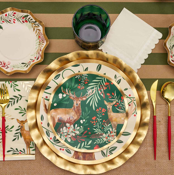 Create a festive tablescape with Sophistiplate's Christmas Forest Table Setting—disposable plates with deer and foliage, gold and red cutlery, green glass, napkins, and striped brown-green tablecloth for any holiday celebration.