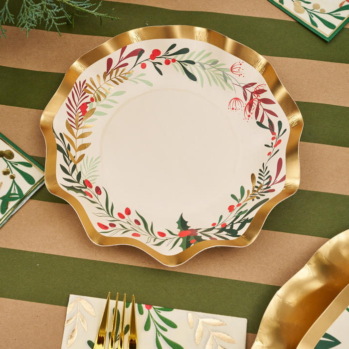 The Sophistiplate Christmas Forest Table Setting features a decorative disposable plate with a gold wavy rim and festive leaf and berry motif, paired with matching napkins and gold utensils for an elegant holiday look.