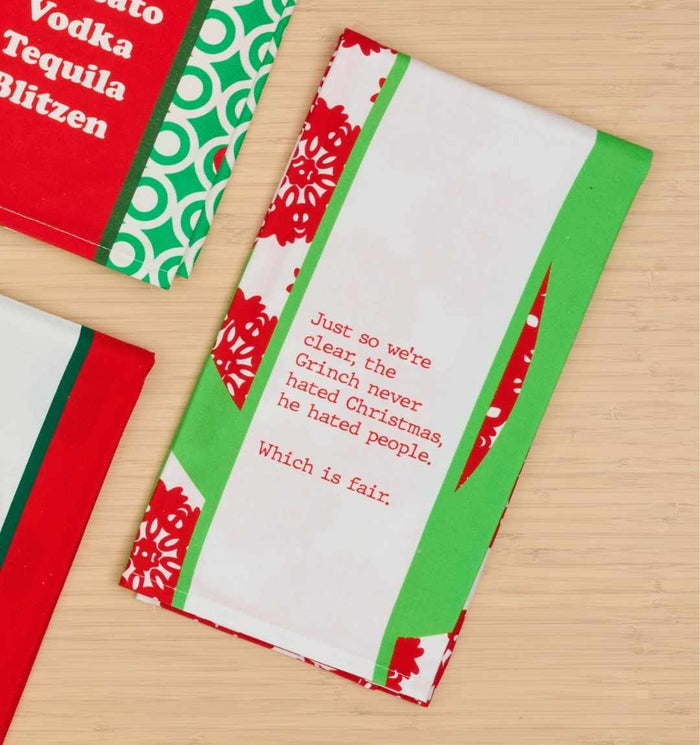 The CHRISTMAS Grinch Dish Towel by Drinks On Me features green and red patterns with the quote: "Just so we're clear, the Grinch never hated Christmas, he hated people. Which is fair." A humorous gift for friends or festive kitchen décor.
