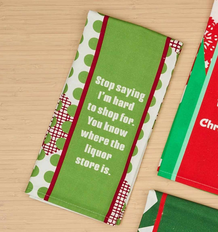 The CHRISTMAS Hard to shop Dish Towel by Drinks On Me is a green and white polka dot kitchen towel with red accents that humorously reads, "Stop saying I’m hard to shop for. You know where the liquor store is.