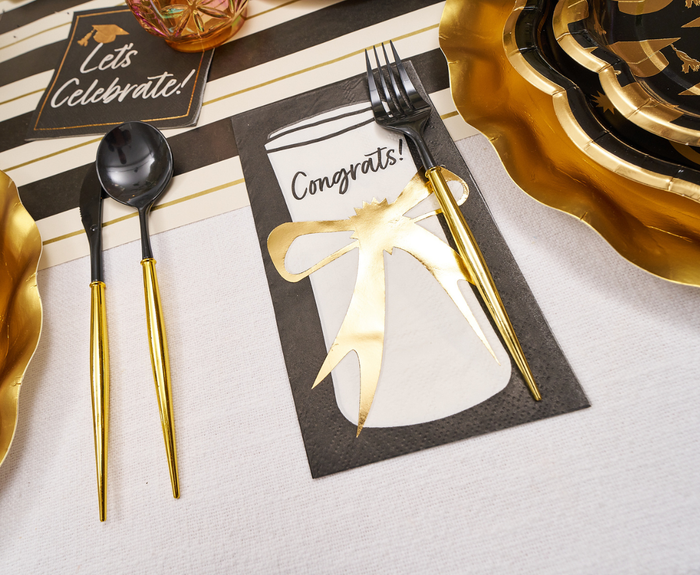 The Sophistiplate Classic Grad Table Setting features black and gold designer plates, a “Congrats!” napkin with gold bow, and a “Let’s Celebrate!” sign—stylish disposable party supplies perfect for graduation celebrations.