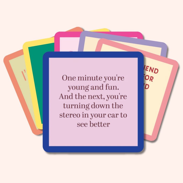 A stack of colorful, funny coasters from Drinks On Me’s Coaster Bundle: Best Sellers sits on top; the first reads, “One minute you’re young and fun. The next, you’re turning down the stereo to see better”—a quirky party gift.