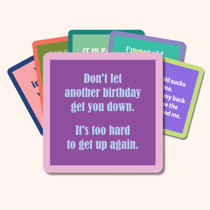 A stack of colorful Drinks On Me Coaster Bundle: Birthday cards with funny messages, featuring a purple card that says: Don't let another birthday get you down. It’s too hard to get up again—perfect for friends or your coaster collection.