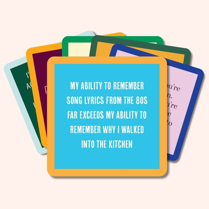 A stack of colorful cards from Drinks On Me’s “Coaster Bundle: Growing Old” features witty sayings like, “My ability to remember song lyrics from the 80s far exceeds my ability to remember why I walked into the kitchen”—a perfect gift for friends.