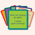A stack of colorful square coasters from the Coaster Bundle: Socially Selective by Drinks On Me, with the front one reading "Here we fucking go again. I mean good morning."—perfect as unique party gifts.