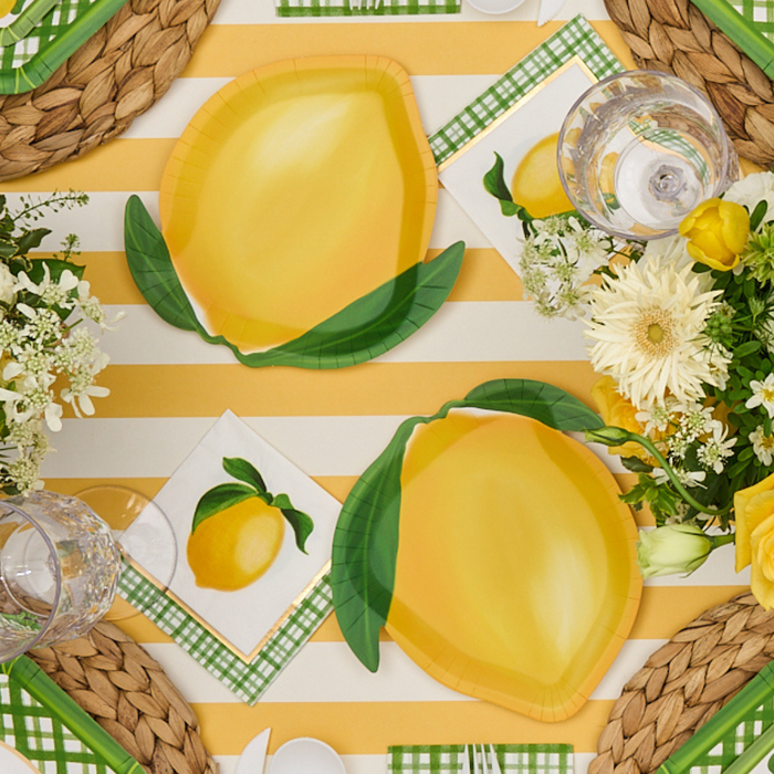 A summer table setting with Sophistiplate Lemon and Stem Salad Plates (8pk), yellow and white striped tablecloth, lemon napkins, green plaid accents, clear glasses, and floral centerpieces—perfect for entertaining.