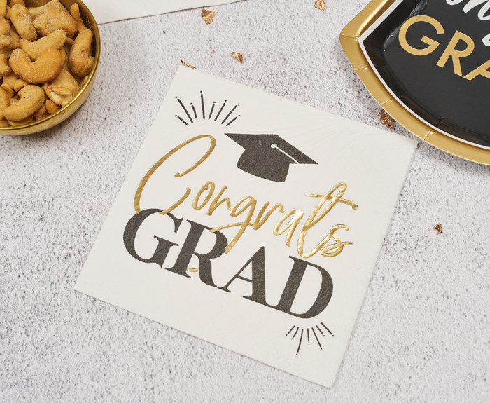 Sugarplum Congrats Grad Cocktail Napkins (26pk) feature gold and black “Congrats GRAD” text with a graduation cap graphic—a stylish choice for your grad party’s snacks and drinks.