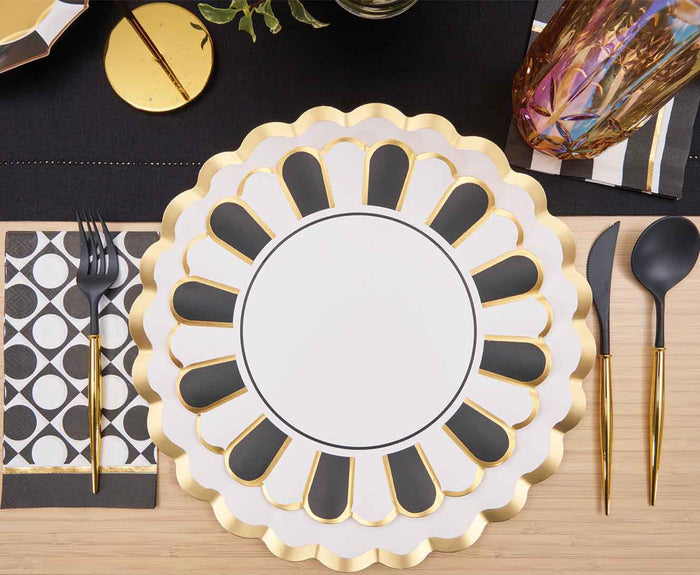 Create an elegant table setting with Sophistiplate’s Cordoba Dinner Plates (8pk), gold-accented black cutlery, a patterned napkin, and a black placemat on light wood—perfect for stylish disposable dining.