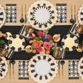 Create a chic tablescape with the Cordoba Table Setting by Sophistiplate LLC, featuring designer gold, black, and white plates, gold cutlery, geometric napkins, and a vibrant floral centerpiece atop a sleek black runner.