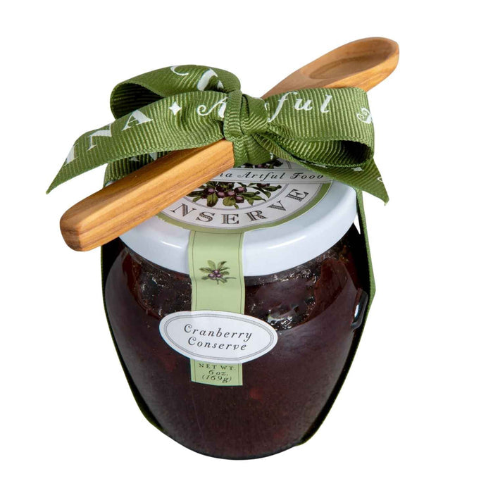 The Bella Cucina Cranberry Conserve Gift w/ Spoon features a jar with a white lid, green ribbon and bow, plus a wooden spoon—an ideal Thanksgiving condiment for fans of sweet and tart flavors.