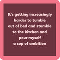 The Cup of Ambition Coaster by Drinks On Me features white text on a dark mauve background with a pink border—perfect as a funny bar cart accessory or unique housewarming gift.