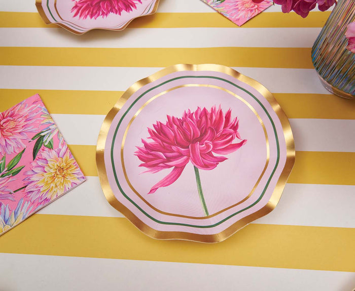 A set of Sophistiplate’s Dahlia Garden Appetizer/Dessert Bowls (8-pack), featuring pink floral designs and elegant gold edging, is displayed on a yellow and white striped table beside a matching floral napkin, a vase of fresh flowers, and coordinating decorative plates—ideal for serving appetizers or desserts at your next gathering.