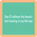 The Day 12 Coaster by Drinks On Me features a green square with a peach border and the text: "Day 12 without the beach: lost hearing in my left eye." A quirky gift for funny drink coaster lovers or housewarmings.