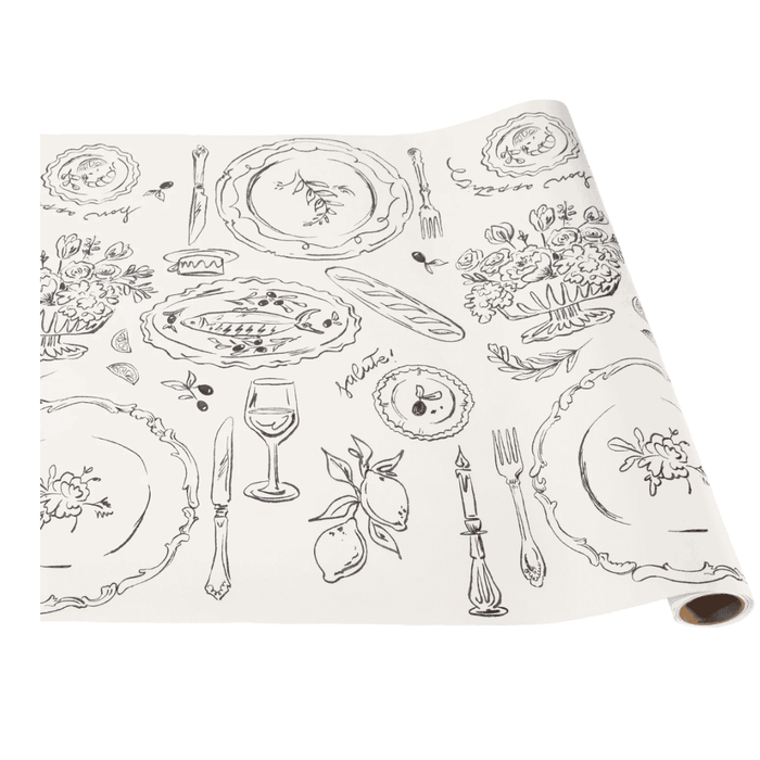The Hester & Cook Dinner Party Runner, 20x25", is a white paper runner with black line art of plates, cutlery, glasses, lemons, flowers, and foods—great for creative table settings or gift wrapping.