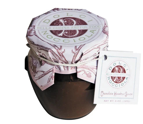 A 6 oz. jar of Bella Cucina Dolci Nocciola Hazelnut Sauce features a decorative paper cover and branded tag, delivering classic Italian flavor in every rich, decadent spoonful.