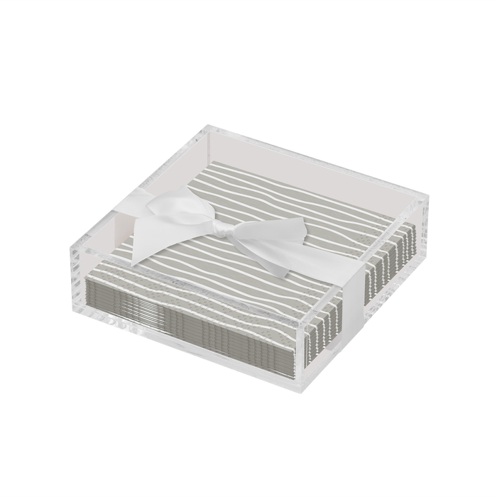 The Sophistiplate Eco Cocktail Napkin with Napkin Tray features white napkins with gray stripes neatly arranged in an acrylic tray and finished with a white satin bow, offering an elegant touch to any modern tabletop.