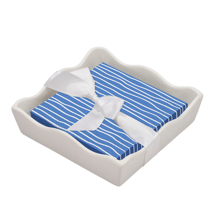 A stack of blue Eco Cocktail Napkins with white stripes by Sophistiplate is neatly arranged in a modern wavy-edged Napkin Tray, all tied together with a white ribbon.