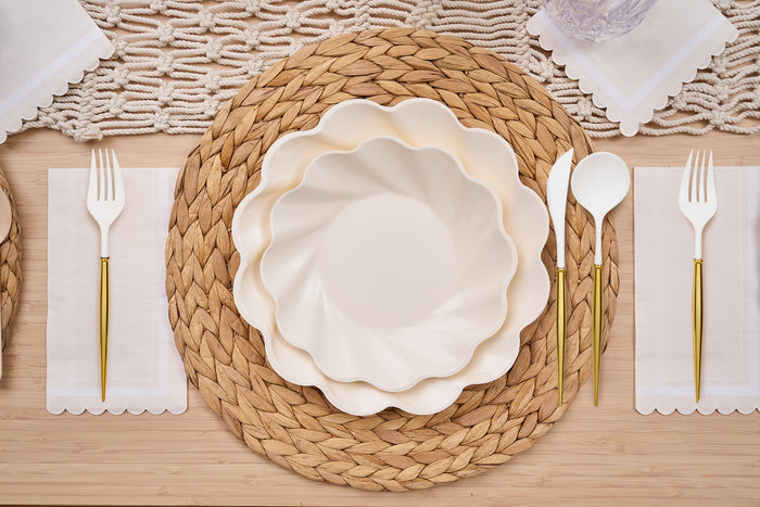 The Sophistiplate Eco-Friendly Table Setting-Cream features a woven placemat, bamboo plates, white napkin, gold and white cutlery, and a decorative table runner on a light wooden table.