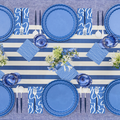 The Sophistiplate Eco-Friendly Table Setting-French Blue features blue plates and glasses, white cutlery, patterned napkins, a striped runner, and floral centerpieces for six—perfect for a chic blue and white tablescape.