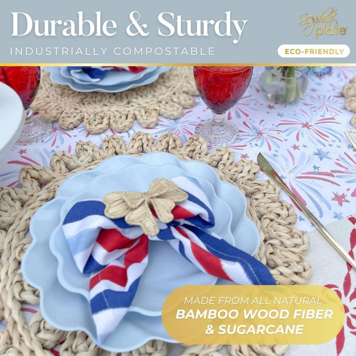A close-up of Sophistiplate’s Eco-Friendly Table Setting- Sky Blue shows compostable party plates, a red, white, and blue napkin with a gold butterfly ring, woven placemats, and red drinks—all made from eco-friendly bamboo fiber and sugarcane.