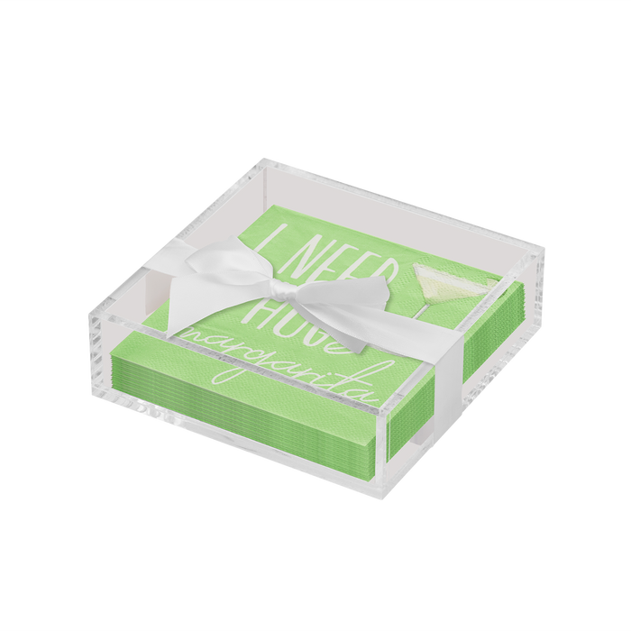 The Sophistiplate Everyday Cocktail Napkin with Napkin Tray features green napkins with “I NEED A HUGe margarita” in white, displayed in a clear acrylic holder and finished with a white ribbon bow.
