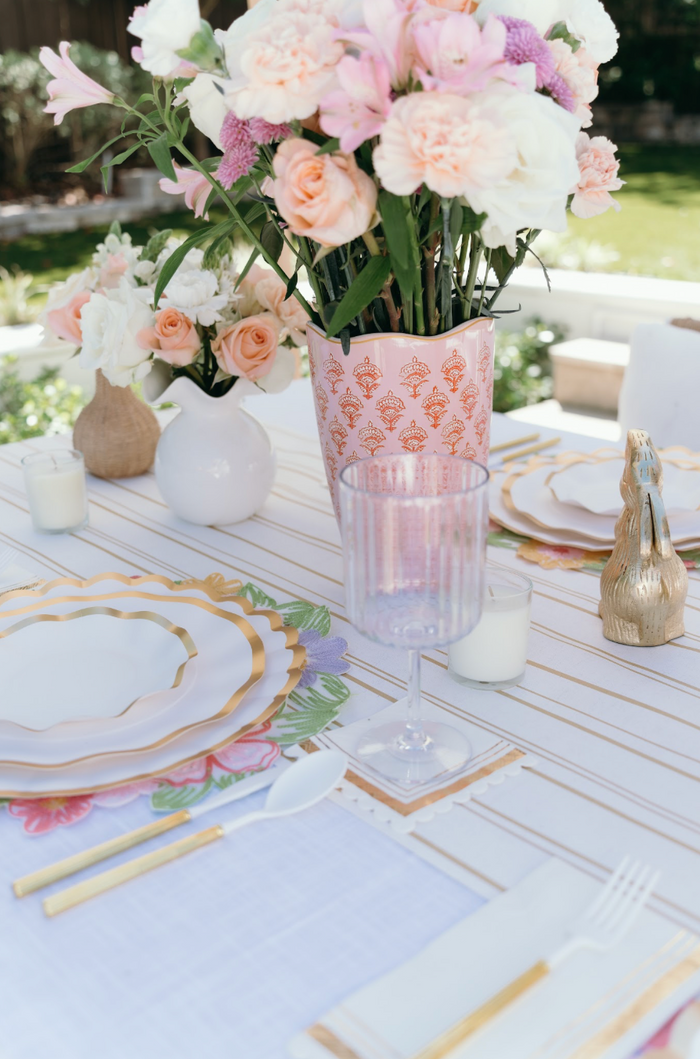 Here’s a rewritten version incorporating the provided product data: An elegant outdoor table set in bright daylight features floral arrangements, Everyday White Salad Plates by Sophistiplate, a pink patterned vase, glassware, candles, and gold utensils on a striped tablecloth in a lush garden setting.