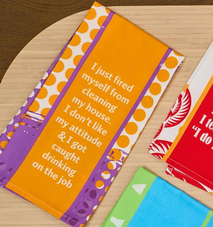 The Fired Dish Towel by Drinks On Me features bold orange, purple, and white designs with the saying: "I just fired myself from cleaning my house. I don’t like my attitude & I got caught drinking on the job.