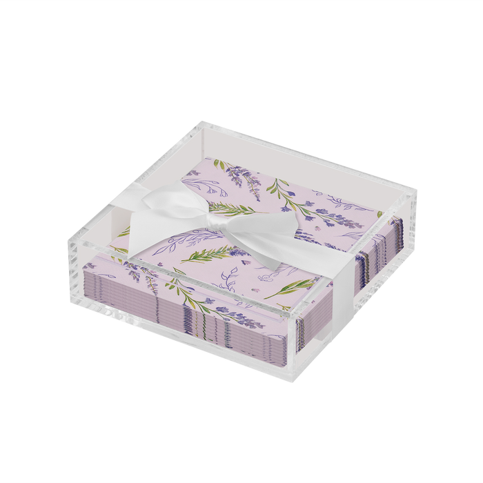 The Sophistiplate Floral Cocktail Napkin with Napkin Tray holds lavender-themed napkins with purple floral designs and green leaves, tied with a white satin ribbon—an elegant addition to your modern tabletop.