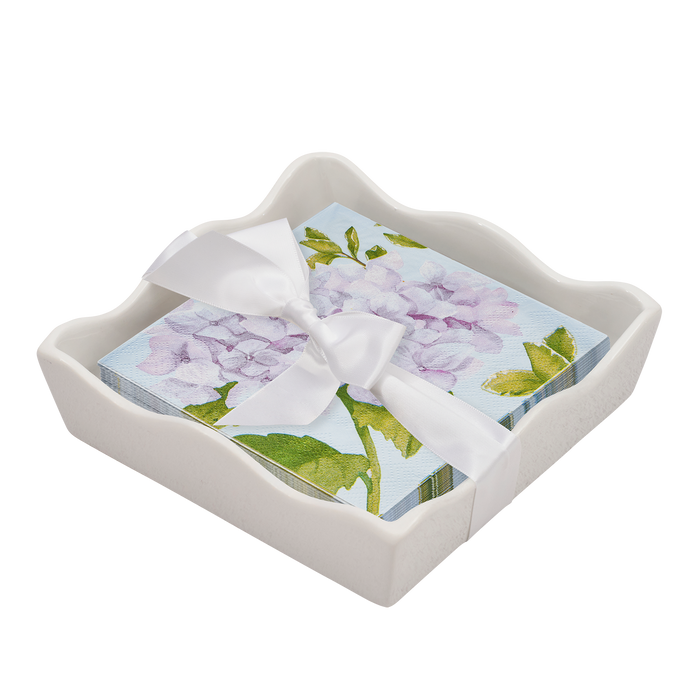 The Sophistiplate Floral Cocktail Napkin with Napkin Tray features purple hydrangea and green leaves napkins, tied with a white ribbon and displayed in a modern white scalloped-edge ceramic tray.