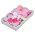 A set of Sophistiplate Floral Guest Towels in a ceramic and acrylic napkin tray, featuring pink dahlia designs, neatly arranged for an elegant touch.