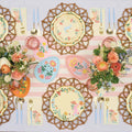 Create a cheerful spring celebration with Sophistiplate LLC's Ultimate Easter Tablescape for 16: Folklore Easter, featuring designer plates, pastel egg decor, gold utensils, a pink striped tablecloth, and floral bouquets.