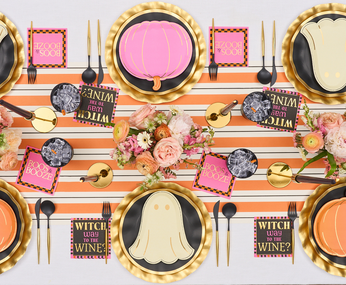 Set a festive Halloween table with a striped orange and white runner, gold plates, pumpkin plates, Sugarplum Boo Bold Assorted Die Cut Salad Plates (8pk), black cutlery, themed napkins, floral centerpieces, and marble-patterned bowls.