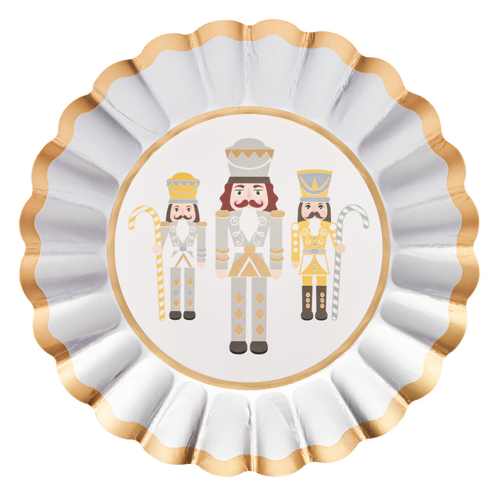 The Sophistiplate Gilded Nutcracker Salad Plates/8pk showcases three nutcrackers in white, gold, and gray uniforms, each holding a staff or candy cane. Accented with elegant gold and silver edges, these decorative plates are a chic addition to your holiday tableware or festive disposable salad plates.