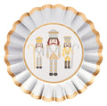The Sophistiplate Gilded Nutcracker Salad Plates/8pk showcases three nutcrackers in white, gold, and gray uniforms, each holding a staff or candy cane. Accented with elegant gold and silver edges, these decorative plates are a chic addition to your holiday tableware or festive disposable salad plates.