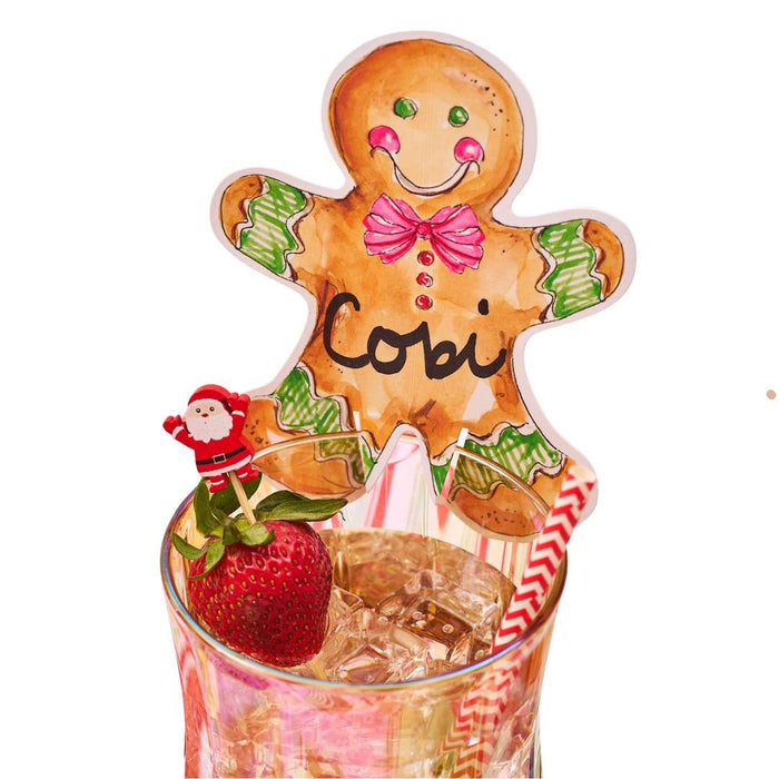 A Rosanne Beck Gingerbread Cookie Cup Place Card from the 10pk sits atop a glass with festive touches—perfect as holiday cup accents or creative Christmas name cards for your table.