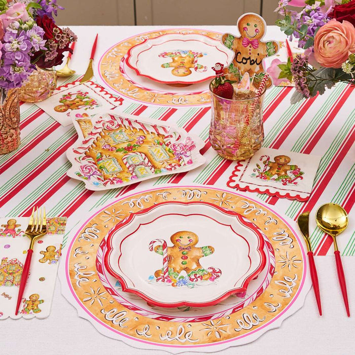 A festive table features Rosanne Beck's Gingerbread Cookie Cup Place Card (10pk), paired with gingerbread-themed plates, striped red, green, and white tablecloth, floral centerpieces, and holiday decor.