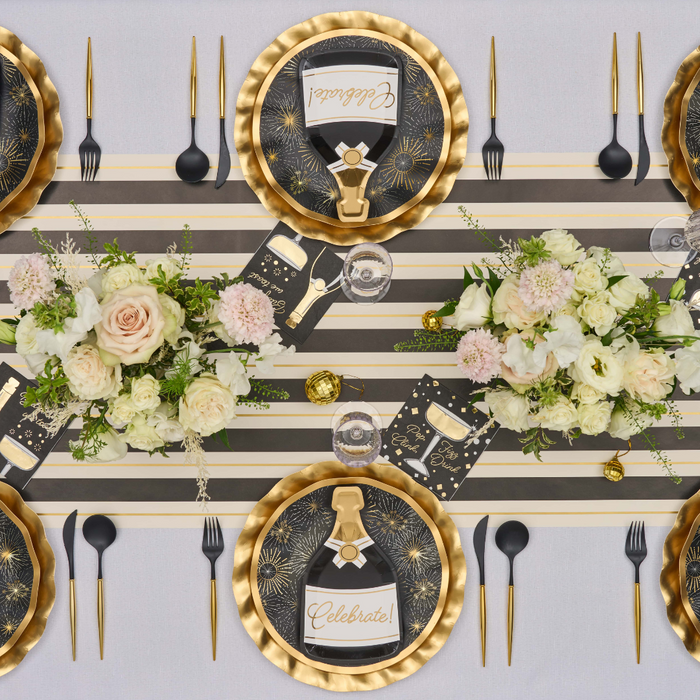 A festive table setting featuring Sophistiplate’s Gold Disco Coupe Dinner Plates (8pk), paired with chic black and gold cutlery, a striped runner, vibrant floral centerpieces, and celebratory napkins adorned with “Celebrate!” in elegant script. The shimmering plates from Sophistiplate add extra sparkle to the arrangement, making every detail perfect for an unforgettable celebration.