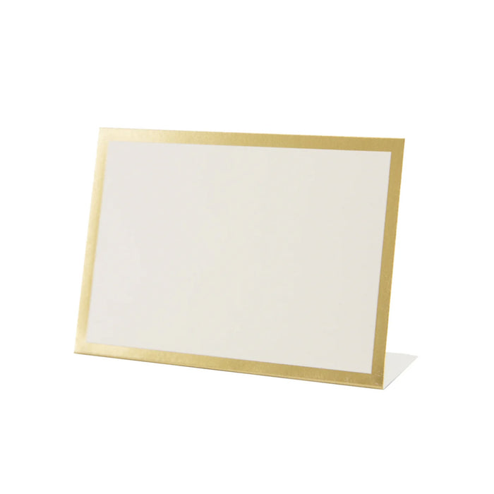 The Hester & Cook Gold Frame Place Card (12ct) stands upright on a white surface at a slight angle, featuring a blank white card with an elegant gold border—ideal for buffet labels or place cards.