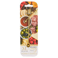 The Maple Meg Quinn Gold Stainless Steel Honey Dipper is packaged on a card with a charcuterie board image and meats, olives, fruit, and honey. The label says “ML x Meg Honey Dipper.”.